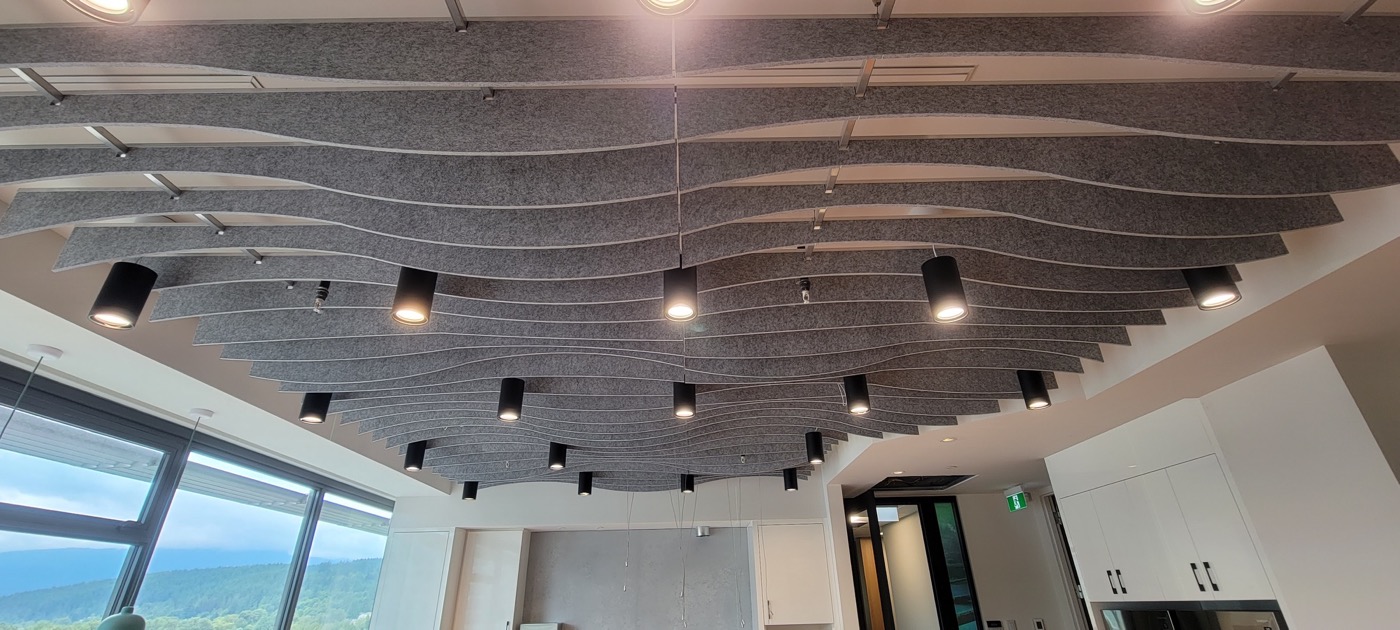 Finished commercial room with a suspended linear baffle ceiling and integrated lighting.