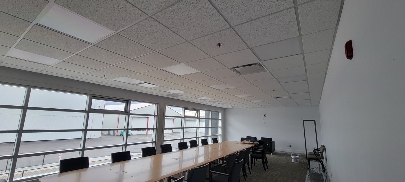Commercial meeting room with completed acoustic ceiling tile and T-bar grid.
