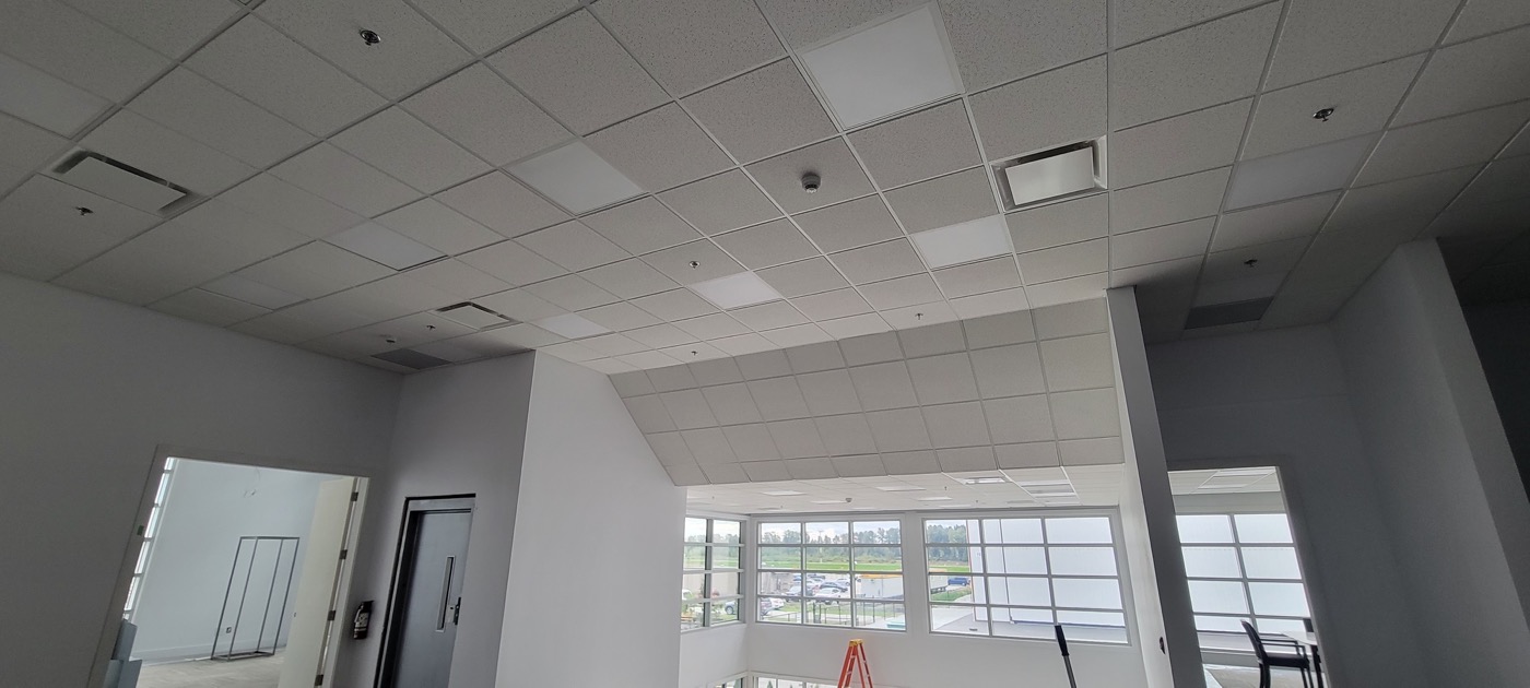 Finished suspended acoustic tile ceiling in a bright commercial room.