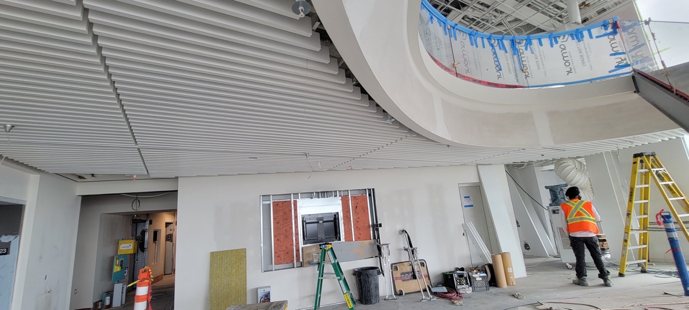 Linear metal ceiling installation around a curved architectural feature.
