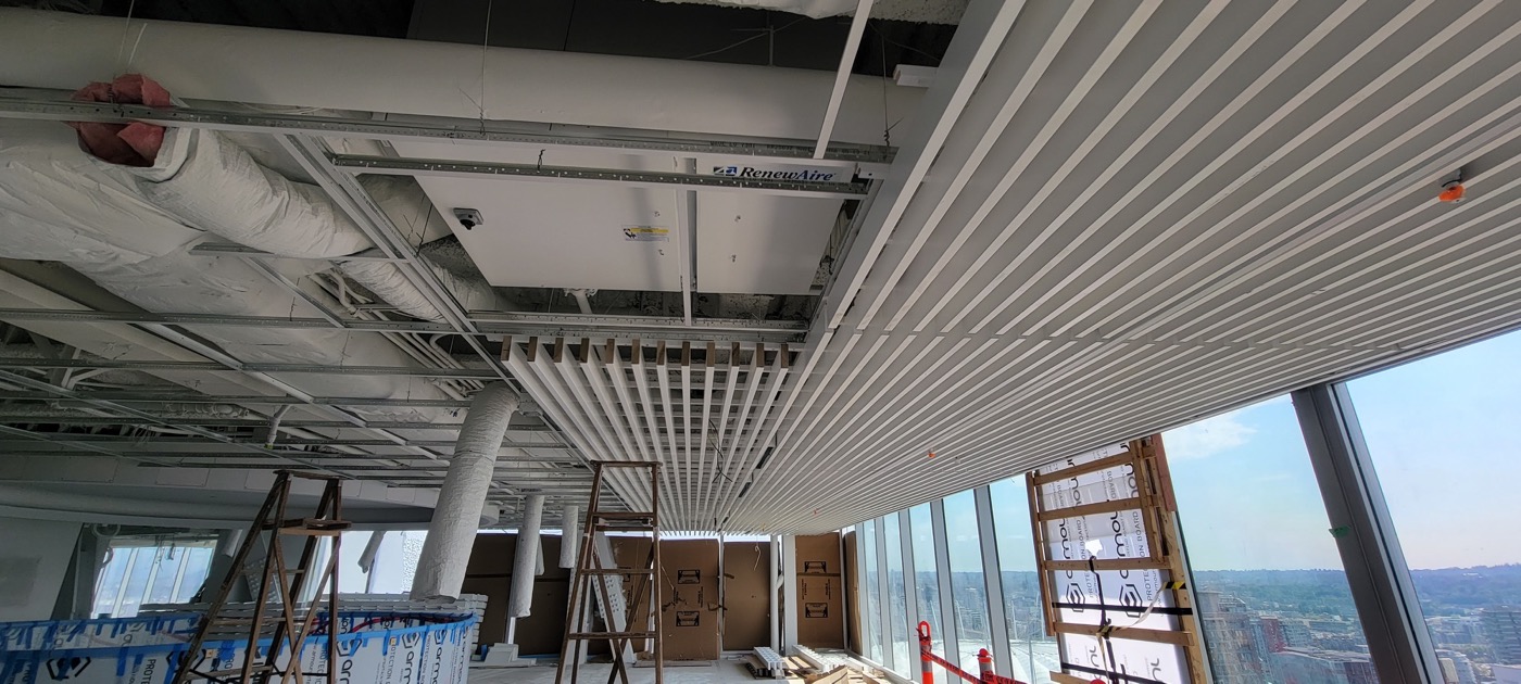 Suspended linear ceiling system installed beneath exposed mechanical services.