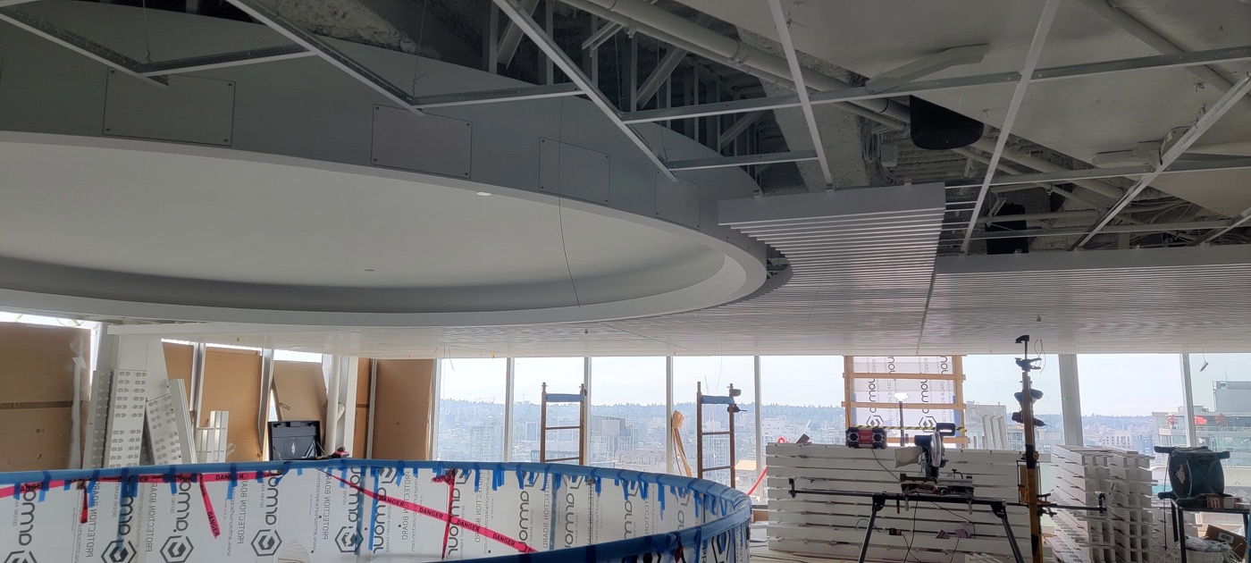 Curved ceiling framing and linear feature ceiling installation in progress.