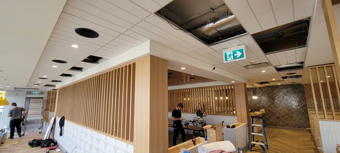 Completed commercial interior with wood-slat architectural ceiling details.