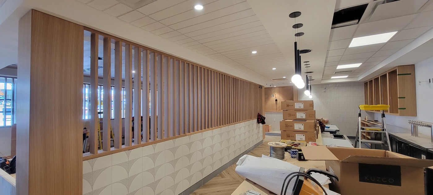 Completed wood-slat partition and ceiling feature at a commercial project.
