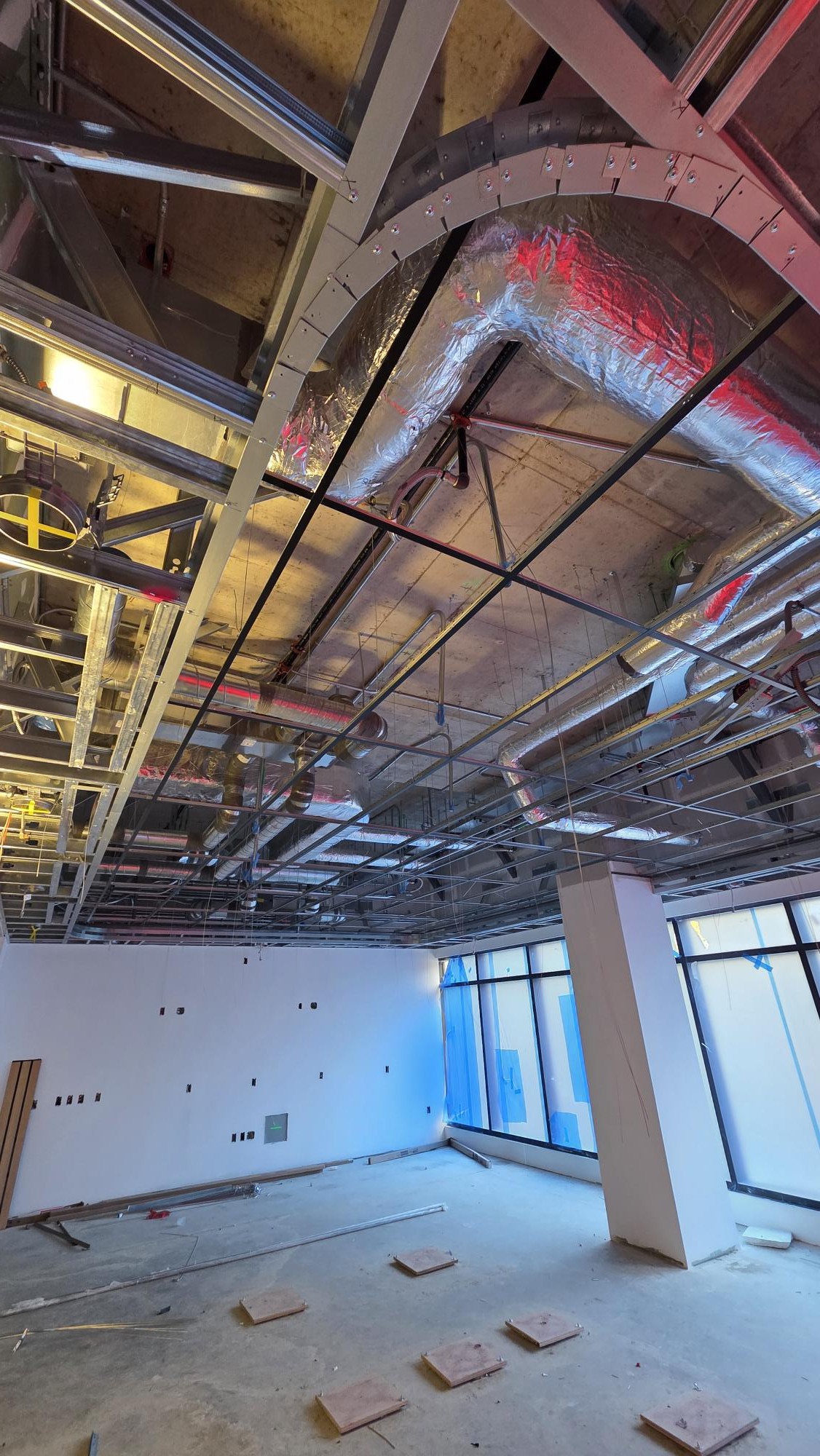 A wider installation view connects the open ceiling grid with the room edges and exposed overhead services.